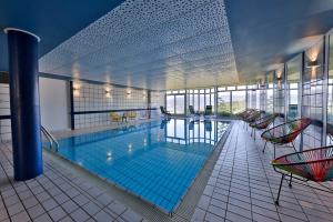 a large swimming pool with chairs and tables in a building at Hôtel Panorama in Munster
