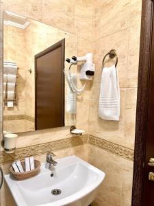 a bathroom with a sink and a mirror and towels at VLG Hotel in Boryspilʼ