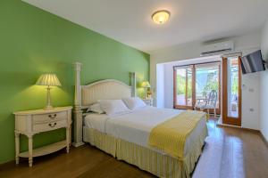 a bedroom with green walls and a bed with a nightstand and a table with at Platanias Memories Apartment in Platanias