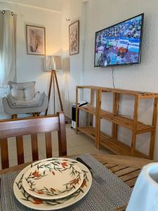 a living room with a table and a tv on the wall at Flat Marezzi - Pé na areia - Taíba CE in São Gonçalo do Amarante