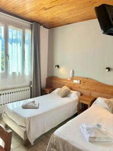 a hotel room with two beds and a window at H&ocirc;tel Sans Souci in Jausiers