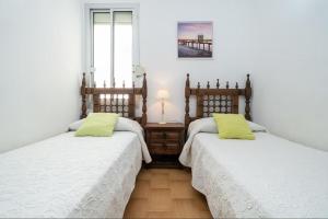 two beds in a room with white sheets and yellow pillows at Mexico I in Cambrils