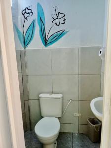 a bathroom with a toilet and flowers on the wall at Recanto Canoa - Canoa Quebrada in Aracati