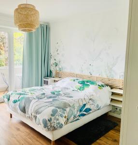 a bedroom with a bed with a floral bedspread at Appartement de standing proche centre ville et gare in Mulhouse