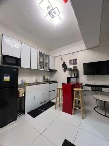 a kitchen with white cabinets and a black refrigerator at JK's Haven in Naga