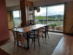 a dining room table with chairs and a large window at Chambre chez Casa Créteil in Créteil
