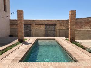 a swimming pool in front of a brick building at Les Cases del Moliner in Corbíns