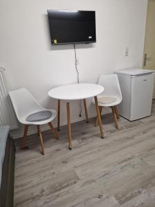 two white chairs and a table and a tv on a wall at Tulpe in Günzburg +17 photos