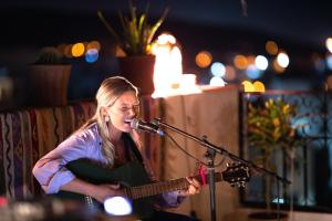 a girl playing a guitar and singing into a microphone at cactus surf house in Tamraght Ouzdar