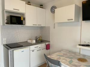 eine kleine Küche mit weißen Schränken und einem Tisch in der Unterkunft charmant studio plage et marché à pied in Pornichet