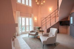 a living room with two chairs and a staircase at Sirocco Maisonette - Kyparissia Old Town Home Collection in Kyparissia