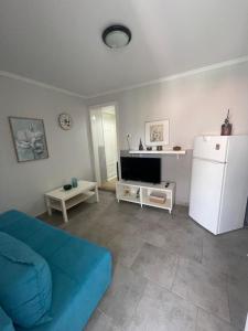 a living room with a blue couch and a refrigerator at Anastelia Apartments - The Backyard in Olympiada