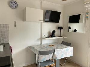 eine Küche mit einem Tisch mit Stühlen und einem TV in der Unterkunft charmant studio plage et marché à pied in Pornichet