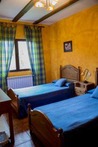 a bedroom with two beds and a table and a window at Apartamentos Rurales Alvado in Tamajón