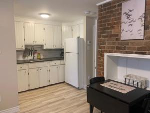 a kitchen with a white refrigerator and a brick wall at Bauer Terrace - Cozy 1 bedroom beside The Citadel in Halifax