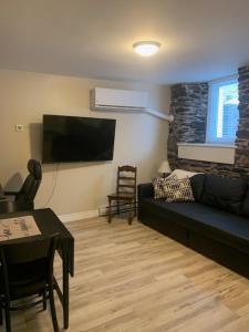 a living room with a black couch and a tv at Bauer Terrace - Cozy 1 bedroom beside The Citadel in Halifax