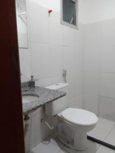 a white bathroom with a toilet and a sink at Hostel Diniz II in Serra +36 photos