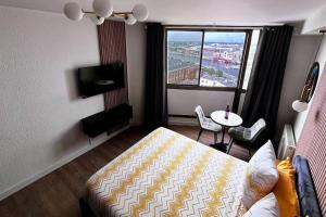 a bedroom with a bed and a table and a window at Studio Les Embruns in Dunkerque +3 photos