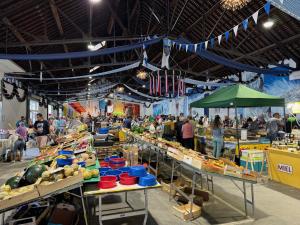 a farmers market with people standing in a large room at La Kaz montagne in Briançon