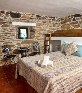 a bedroom with a bed and a stone wall at Casa Da Oliveira in Pedrógão Grande