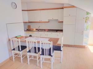 une cuisine avec des armoires blanches et une table et des chaises dans l'établissement Ático Agarimos do Mar, à Corcubión