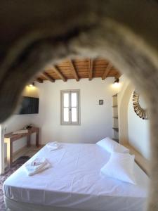 a bedroom with a large white bed with a window at Tinian View Bee Home Maisonette in Arnados