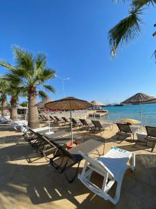 a group of lounge chairs and umbrellas on a beach at Kalipso motel in Çeşme +40 photos