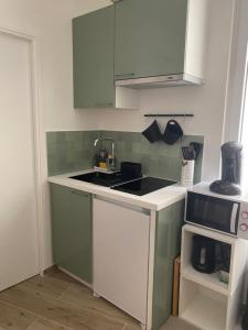 eine Küche mit grünen und weißen Schränken und einer Spüle in der Unterkunft Studio hyper centre proche RER in Saint-Germain-en-Laye