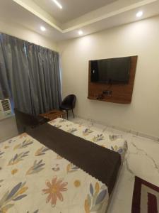 a bedroom with a bed and a tv on the wall at Hotel Mount view inn in Rishīkesh