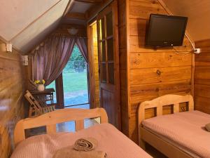 a room with two beds and a television in a cabin at Bungalow Bay -2 domki 4 osoby in Łacha