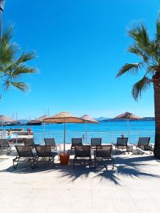 a group of chairs and umbrellas on a beach at Kalipso motel in Çeşme