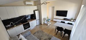 a kitchen with white cabinets and a table and a dining room at Garden beach house in Hamallë