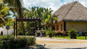 a building with a thatched roof and palm trees at Unique Pool & Golf view retreat 1BR in Hard Rock in Punta Cana