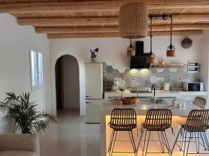 a kitchen with a island with bar chairs and a sink at Villa Iasmos in Pitsidia
