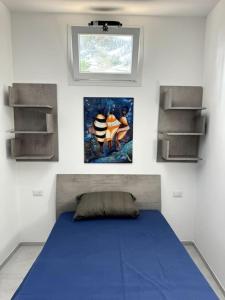a bedroom with a blue bed and a painting on the wall at Casa vacanze Tramontana Salentina in Lendinuso