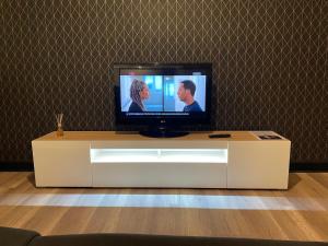 a television sitting on top of a white entertainment center at Grand Appartement Lumineux au Centre d'Aurillac in Aurillac +16 photos
