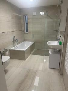 a bathroom with a tub and a toilet and a sink at Quiet 1-Bedroom Apartment - Ideal for small Familiy & Work Stays in Munich +8 photos