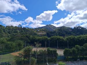 a tennis court with a mountain in the background at Apartamento Centro ao lado do Country Club in Nova Friburgo