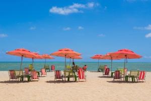 a group of chairs and umbrellas on a beach at Flat 10 andar Hotel Caesar Towers acesso direto praia in Recife