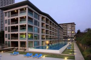 a building with a swimming pool and blue lounge chairs at Ananya Beachfront Wongamat Paradise in North Pattaya