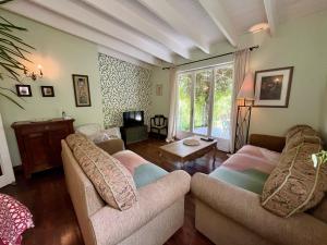 a living room with two couches and a tv at Le Coin Caché in Le Vigeant