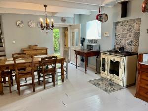 a kitchen and dining room with a table and a stove at Le Coin Caché in Le Vigeant