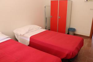 a room with two beds and a red cabinet at Ostello Paradiso EuroCamp in Cesenatico
