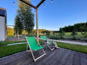two chairs and a table on a wooden deck at Domki Na Łące in Święta Katarzyna