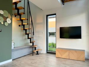 a living room with a staircase and a flat screen tv at Domki Na Łące in Święta Katarzyna