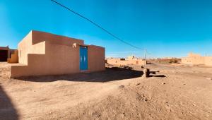 a small building with a blue door in the desert at maison traditionnelle in Merzouga