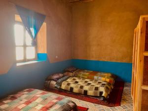 two beds sitting in a room with a window at maison traditionnelle in Merzouga