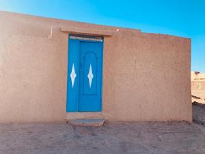a blue door on the side of a building at maison traditionnelle in Merzouga +7 photos
