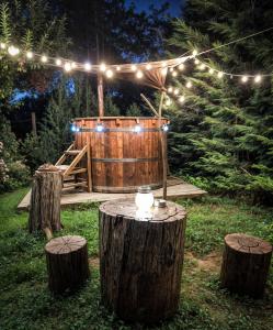 a wooden barrel with lights on top of some logs at Pensiunea Cocoș in Spulber