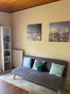 a couch in a living room with two pictures on the wall at Appartement avec jardin in Le Porge
